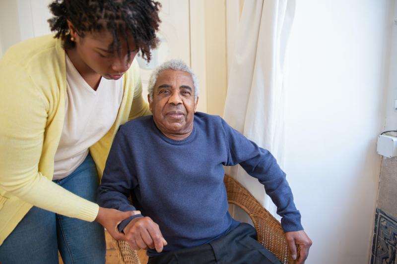Older Adult Being Assisted in Chair by Caregiver